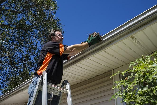 man using a ladder to fix a broken gutter in Bristol, RI